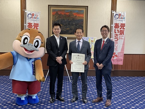 コーナン商事株式会社 疋田代表取締役社長、もずやん、水野教育長と記念写真を撮影する知事