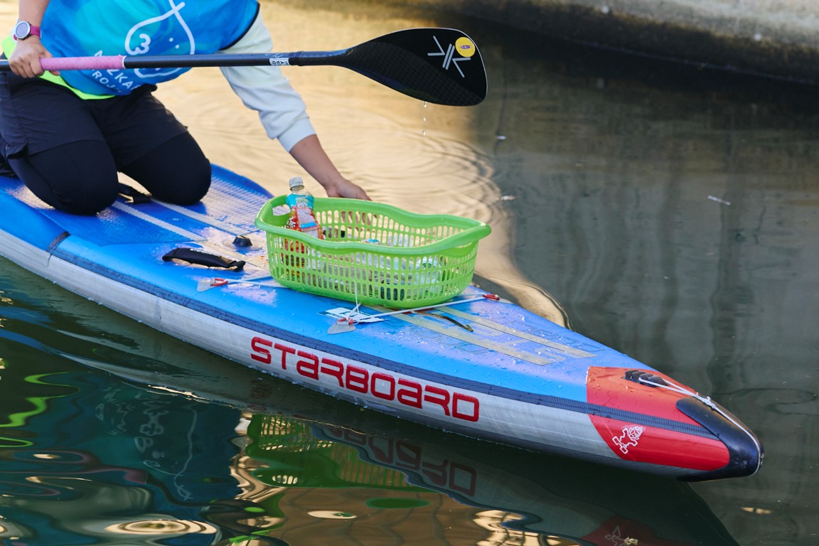 一人乗りサップボードに乗った参加者がごみを拾っている様子