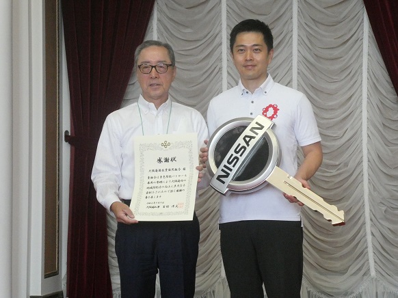 自動車キーを持つ知事と感謝状を持つ平川理事長による写真撮影